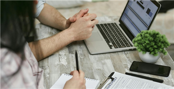 image of two adults with a laptop and taking notes