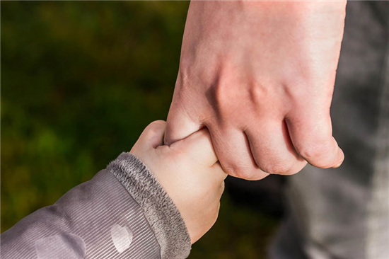 image of an adult holding a child\'s hand